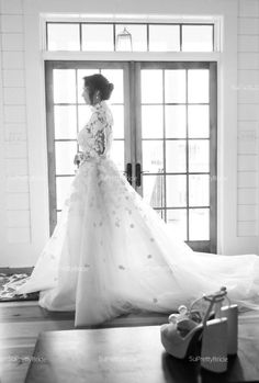 a woman standing in front of a door wearing a wedding dress with flowers on it