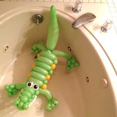 an inflatable green lizard is sitting in the bathtub with its mouth open