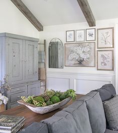 a living room with gray couches and pictures on the wall above it's coffee table