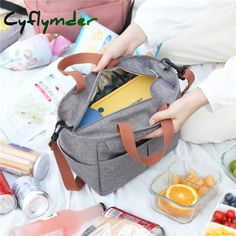 a person holding onto a gray bag on top of a white table filled with food