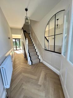 an empty hallway with wooden floors and white painted walls, along with a mirror on the wall