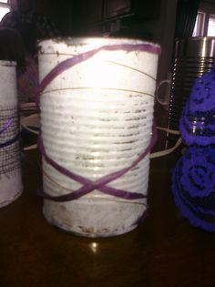 three white buckets sitting on top of a wooden table with purple string wrapped around them