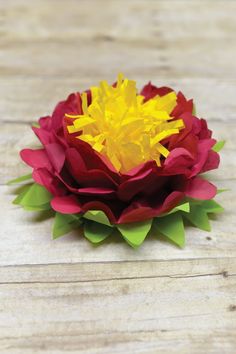 a red and yellow flower sitting on top of a wooden table