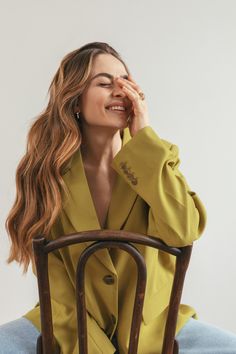 a woman sitting in a chair with her eyes closed and hands behind her head, smiling