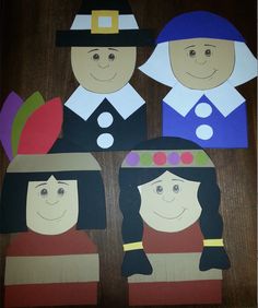 paper cutouts of three people with hats and flowers in the middle, on top of a wooden table