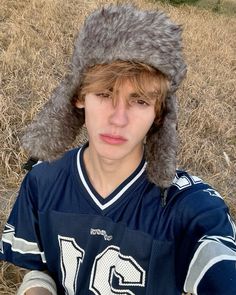 a young man wearing a football uniform with a furry hat on