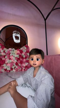 a doll sitting on top of a bed next to a pink flower covered headboard