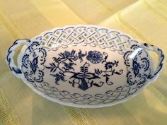 a blue and white bowl sitting on top of a yellow table cloth with an intricate design