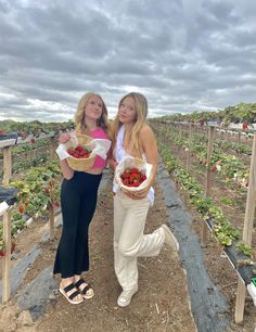 two women holding baskets full of strawberries