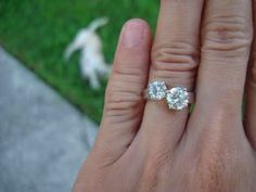 a woman's hand with two diamond rings on it and a dog in the background