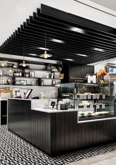 the interior of a restaurant with black and white tile flooring on the walls, along with shelves filled with food