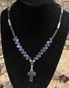 This is a handmade cross necklace that combines natural beads with some faceted beads to really shine.  The colors include purple, green and clear stones strung on a green hemp cord with silver spacers.  This has a button closure and is about 18 inches with about a 1.5 inch drop.  The cross measures 1 inch long.  Really pretty. Handmade Adjustable Cross Pendant Necklace, Adjustable Spiritual Cross Necklace, Adjustable Bohemian Cross Beaded Necklaces, Adjustable Cross Necklace With 8mm Beads, Macrame Cross, Beaded Macrame, Cross Necklaces, Hemp Cord, Fabric Yarn