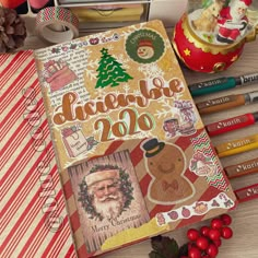 an open christmas planner surrounded by holiday decorations and crayon pencils on a table