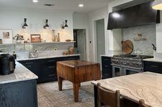 a kitchen with marble counter tops and black cabinets, along with an island in the middle