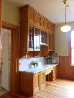 an empty kitchen with wooden cabinets and white counter tops on hard wood flooring in front of a window