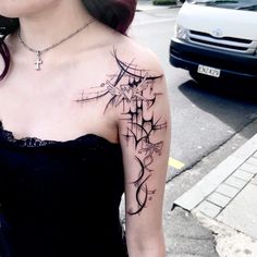 a woman with a cross tattoo on her arm and shoulder is standing in front of a car