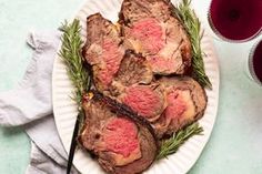 a white plate topped with steak next to two glasses of wine