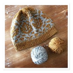 two balls of yarn sitting on top of a wooden table next to a ball of yarn