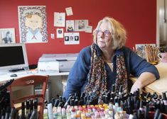 an older woman sitting at a desk with lots of nail polish