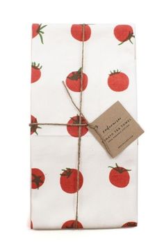 a white napkin with red tomatoes on it and a brown tag hanging from the side