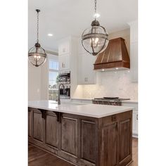 a kitchen with an island and two lights hanging from the ceiling