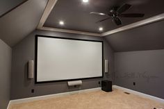 an empty room with a projector screen in the middle and ceiling fans on either side