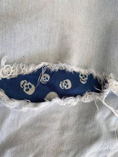 a piece of fabric with skulls on it and torn in half by the end of an old pair of jeans