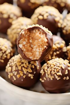 chocolate covered candies with nuts and sprinkles in a white bowl on a table