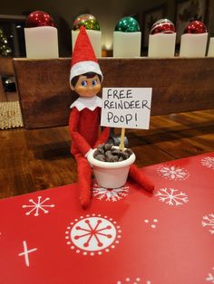 an elf with a free reindeer poop sign sitting in front of a bowl of cookies