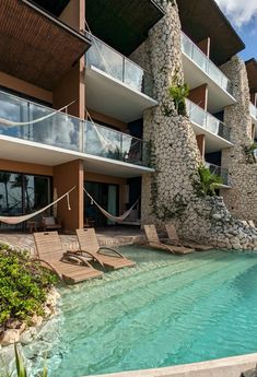 an outdoor swimming pool with hammocks and lounge chairs next to the hotel's balconies