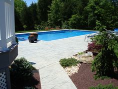 an empty backyard with a pool and landscaping