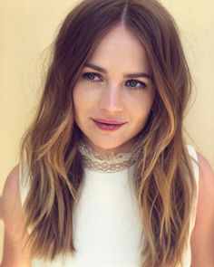 a close up of a person wearing a white shirt and long hair with brown highlights