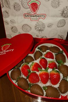 chocolate covered strawberries in a heart shaped box with strawberry house stickers on it