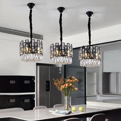 a chandelier hanging over a dining room table with flowers in the vase on it