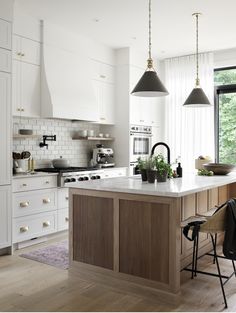 a kitchen with white cabinets and an island that has two stools in front of it