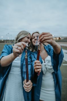 two women holding up their graduation caps and tassels