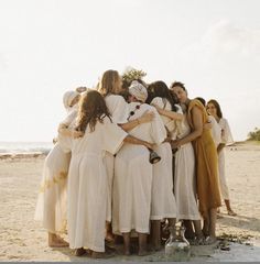 a group of women hugging each other on the beach