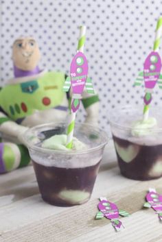 two plastic cups filled with green and purple jello next to toy buzz lightyear figures