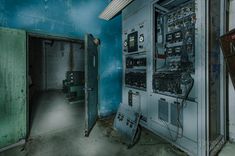 an electrical panel in the corner of a room with blue walls and peeling paint on it