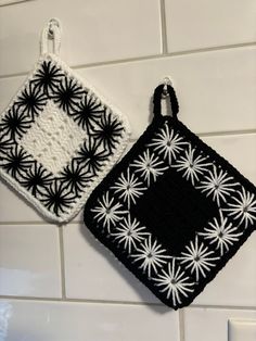 two small black and white squares hanging on the wall next to each other, one has a crocheted square in the middle