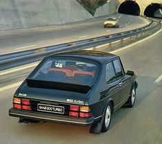 a black car driving down a highway next to a tunnel