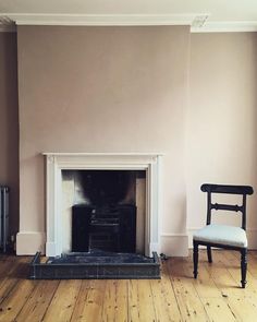 an empty living room with a chair and fireplace