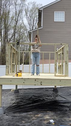 a woman standing on top of a wooden deck in front of a house under construction