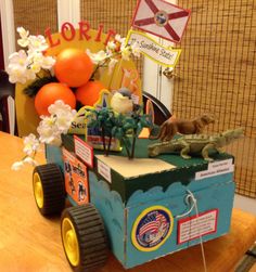 a toy truck with an alligator on the back and flowers in the front sitting on a table