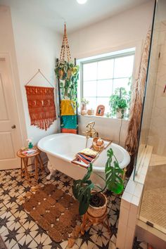 a bathroom with a bathtub, rug and potted plants on the floor in it