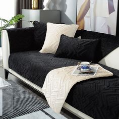 a black couch with white pillows and a tray on the end table in front of it