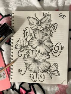 a notebook with flowers and butterflies on it next to a pink phone, pencil and marker