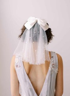 the back of a woman wearing a veil with flowers and pearls on it's head