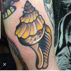 a close up of a person's arm with a tattoo on it and a sea shell