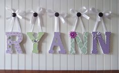 the name ryan is made out of letters with ribbons and flowers hanging on it's wall